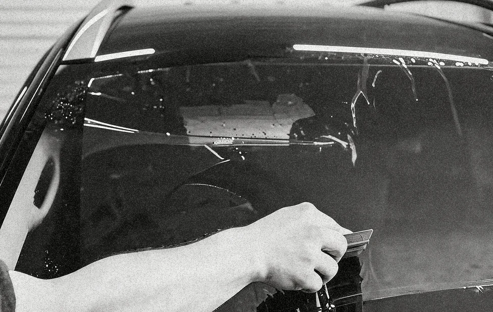 Installer wet-applying protective film to a vehicle windshield