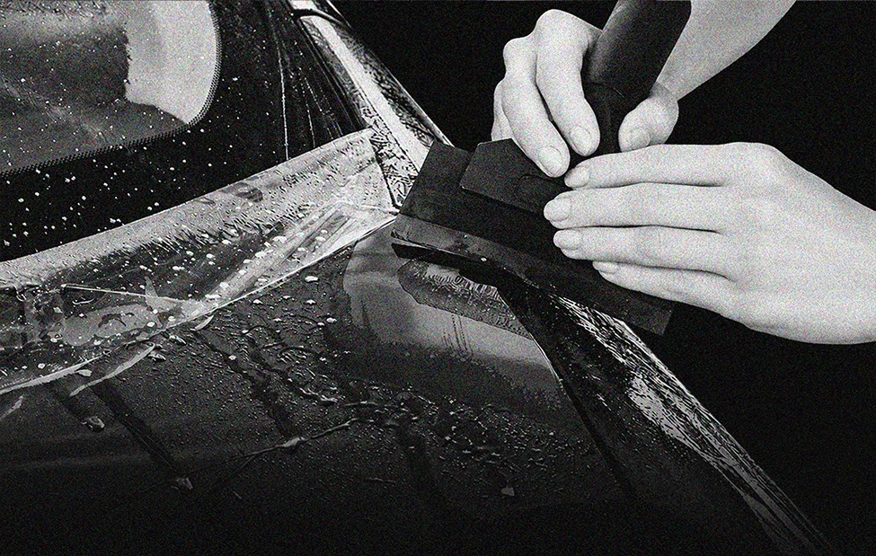 Installer applying clear paint protection film to a vehicle panel with a squeegee