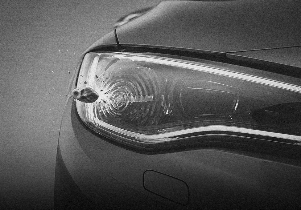 Road debris striking a vehicle headlight lens